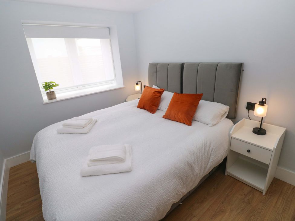 A bedroom with a large bed and bedside tables at Y Bwthyn Burry Port