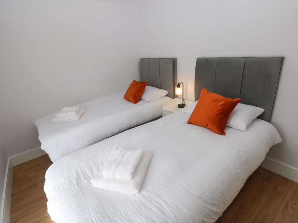 A bedroom with two single beds and a nightstand at Y Bwthyn Burry Port
