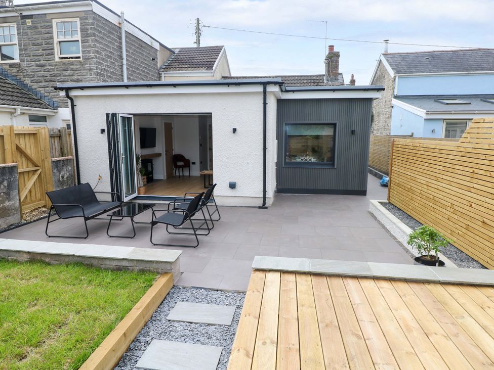 An outdoor patio with chairs and a table at Y Bwthyn Burry Port