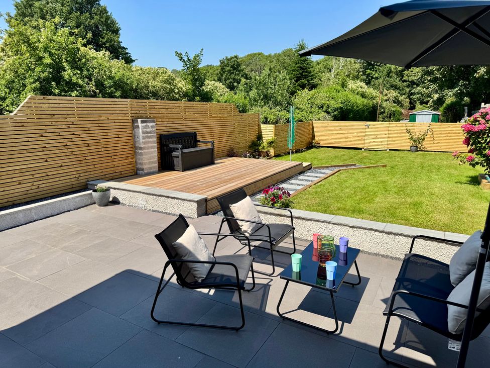 A garden with outdoor furniture and deck at Y Bwthyn in Pembrey