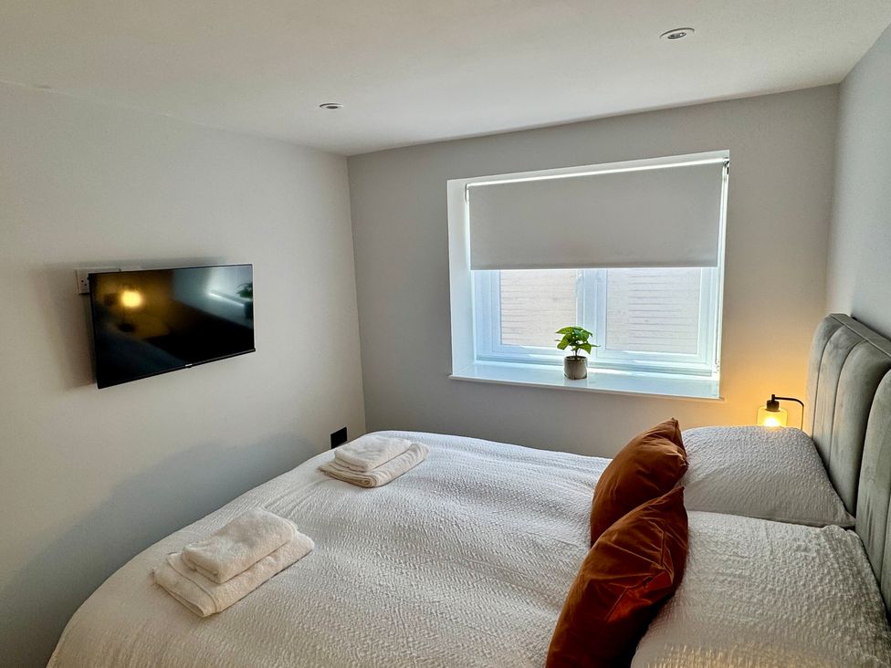 A bedroom with a bed, television, and window at Y Bwthyn in Pembrey