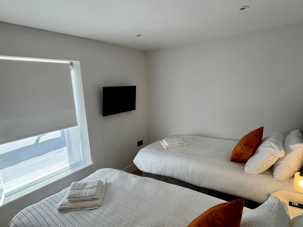 A bedroom with two beds and a television at Y Bwthyn in Pembrey