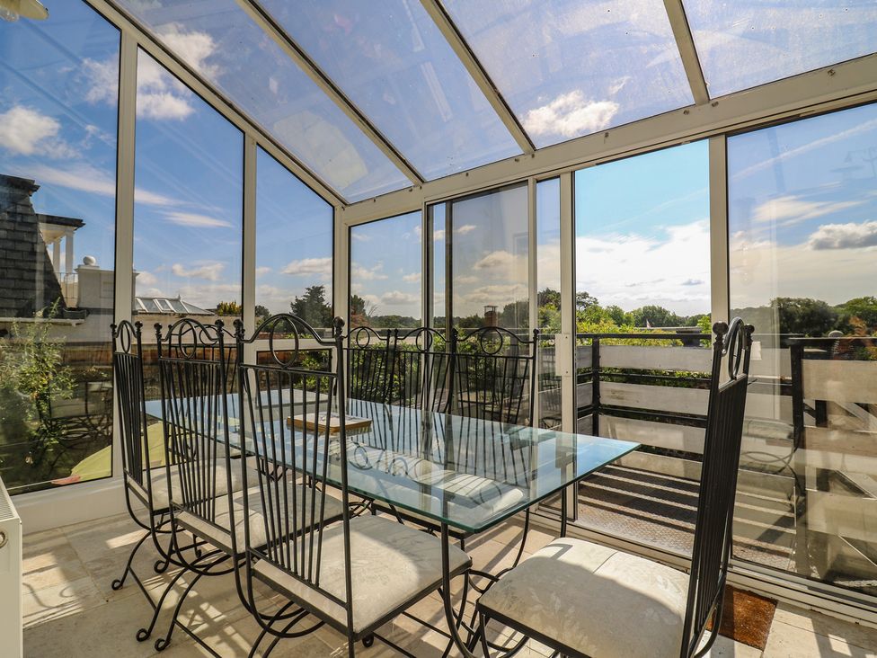 A conservatory with a glass table and chairs at Beresford House in Woodbridge