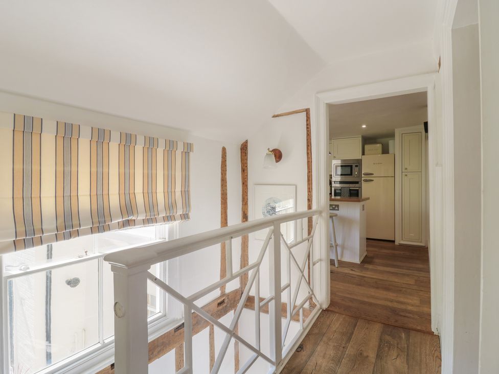 A hallway with a railing and doorway leading to a kitchen at Beresford House in Woodbridge