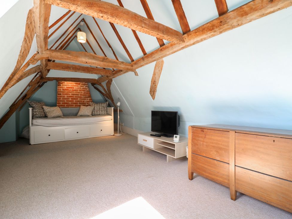 An attic with a sofa bed and a television at Beresford House in Woodbridge