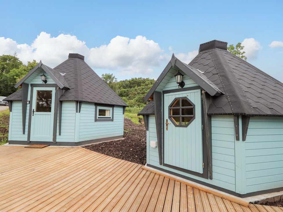 Two wooden huts with angled roofs and decking at Little Luxe Lodges 1 in Kyle