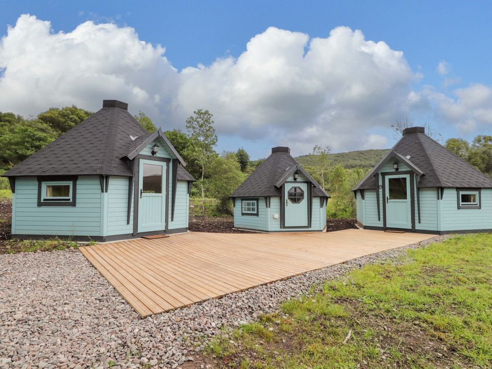 Three wooden huts with a deck area at Little Luxe Lodges 1 in Kyle