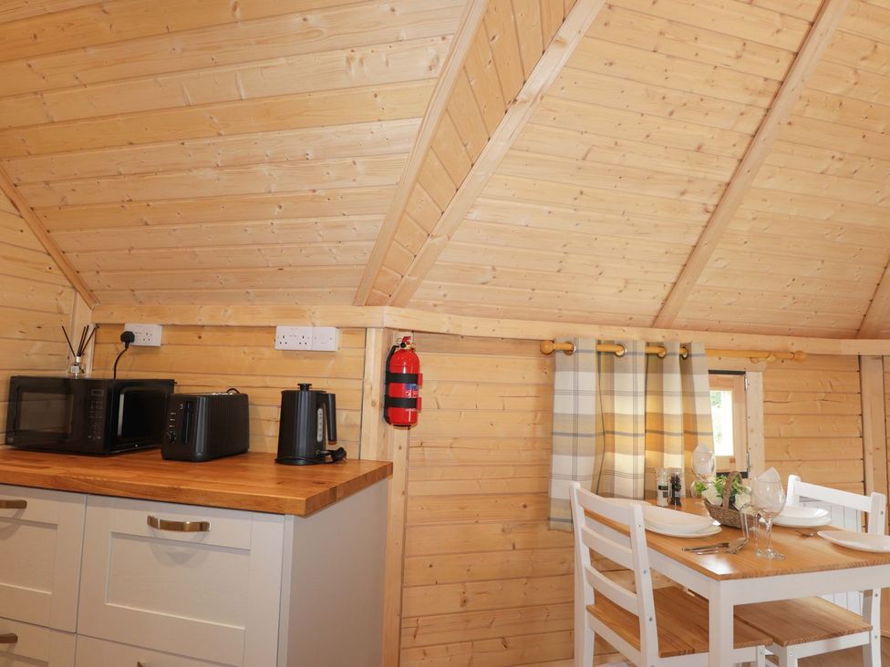 A kitchen with a microwave, toaster, kettle, and dining table at Little Luxe Lodges 2 in Kyle