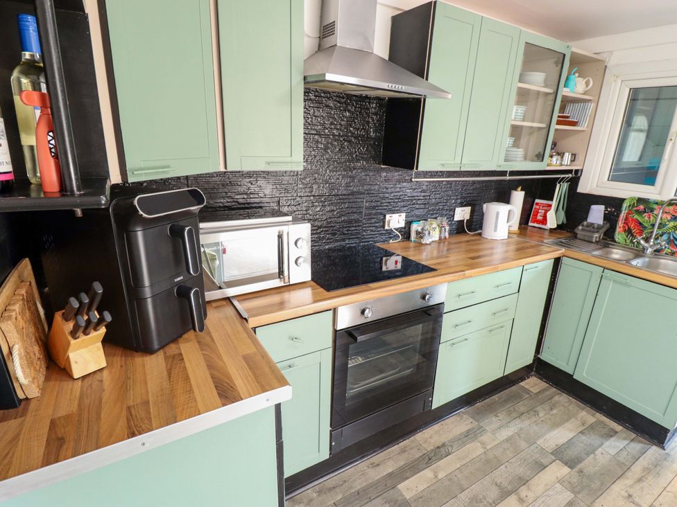 A kitchen with cabinets, oven, microwave, and sink at Four Seasons in Humberston, Lincolnshire