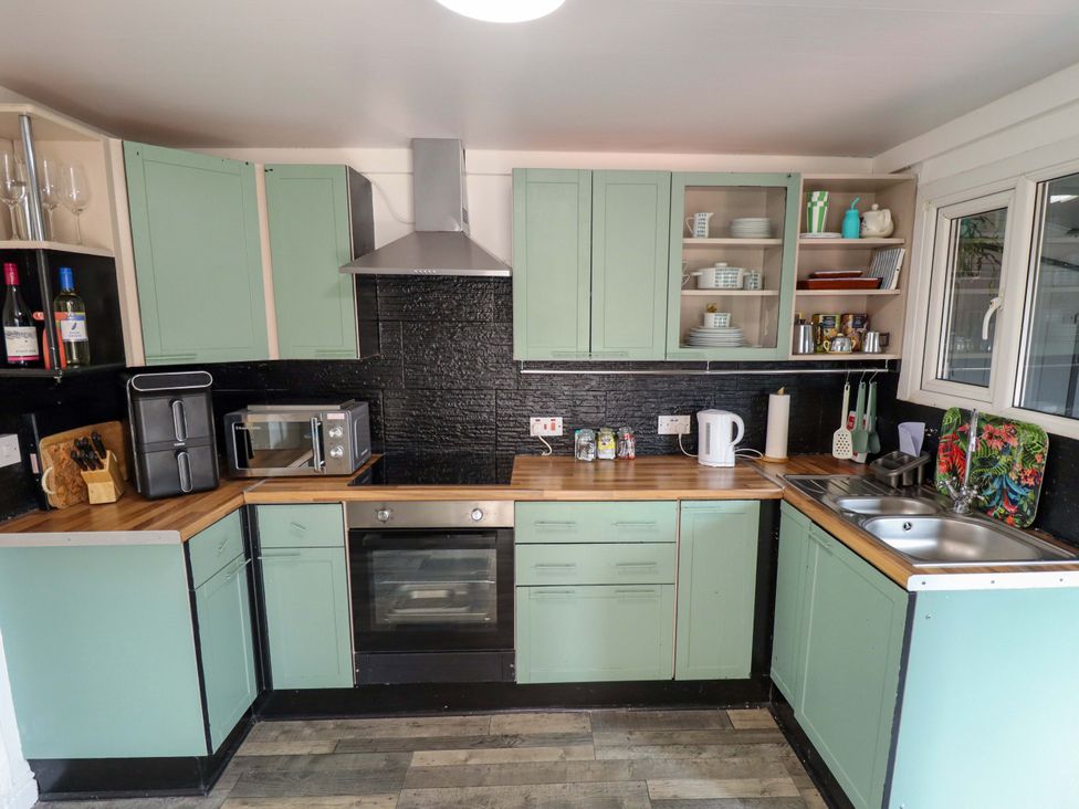 A kitchen with cabinets, sink, stove, and microwave at Four Seasons in Humberston, Lincolnshire