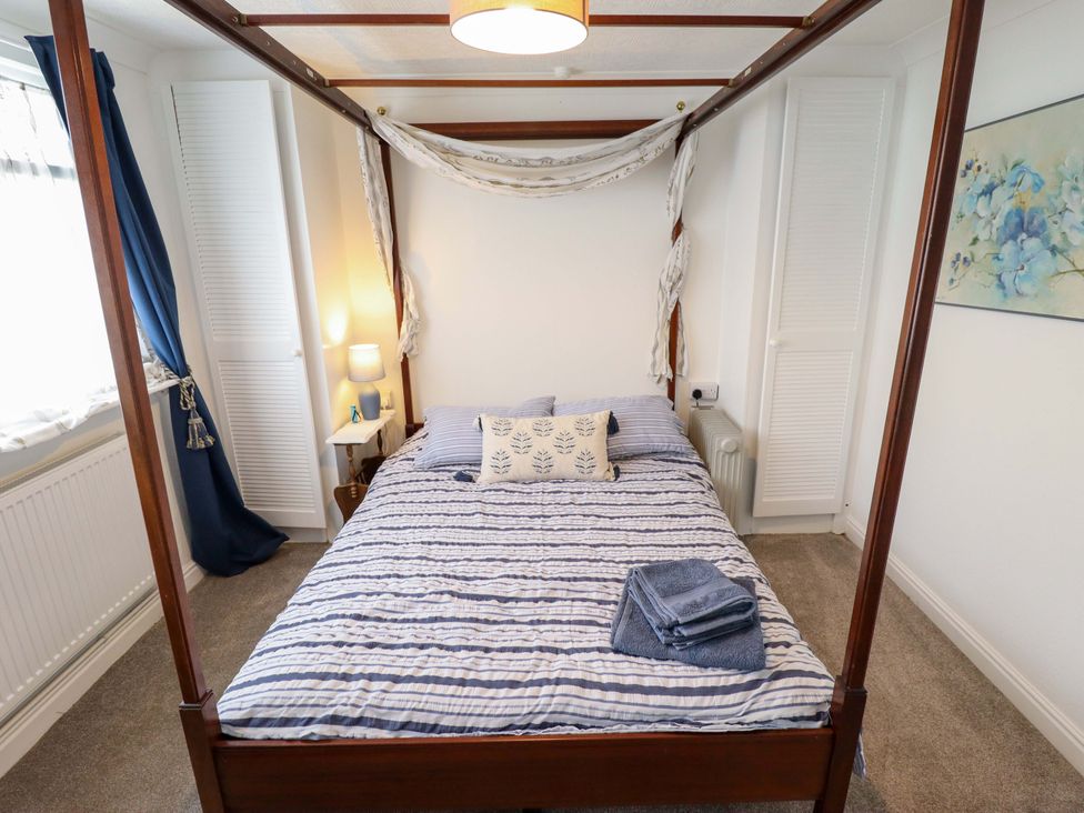 A bedroom with a four-poster bed and bedside table at Four Seasons in Humberston, Lincolnshire