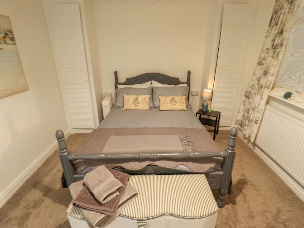 A bedroom with a bed and side table at Four Seasons in Humberston, Lincolnshire