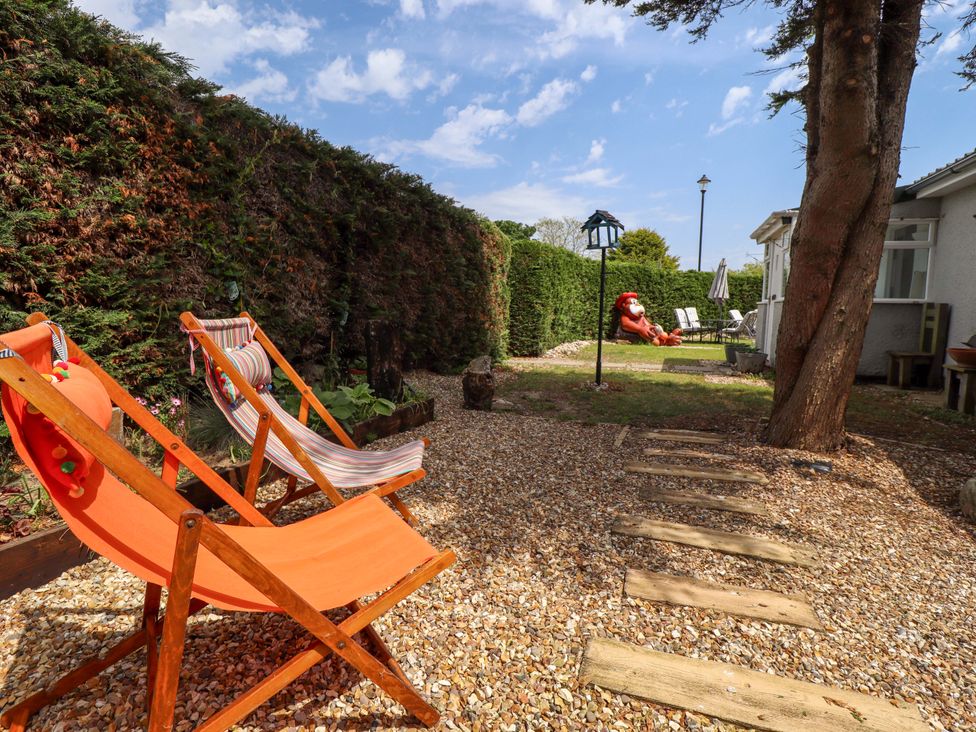 A garden with deck chairs and a pathway at Four Seasons in Humberston, Lincolnshire