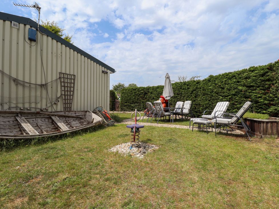 A garden with a boat and seating area at Four Seasons in Humberston, Lincolnshire