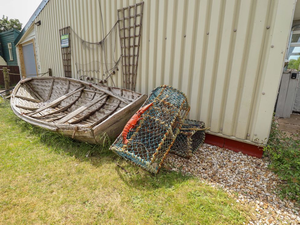 A boat and fishing traps beside a building at Four Seasons, Humberston, Lincolnshire