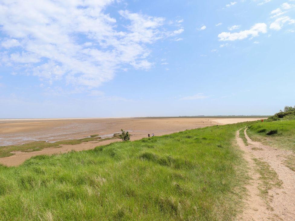 A path alongside grass with people walking near the shore at Four Seasons in Humberston, Lincolnshire