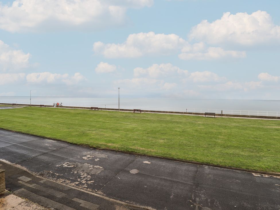An outdoor view of grass and benches overlooking the sea at Sandringham in Withernsea