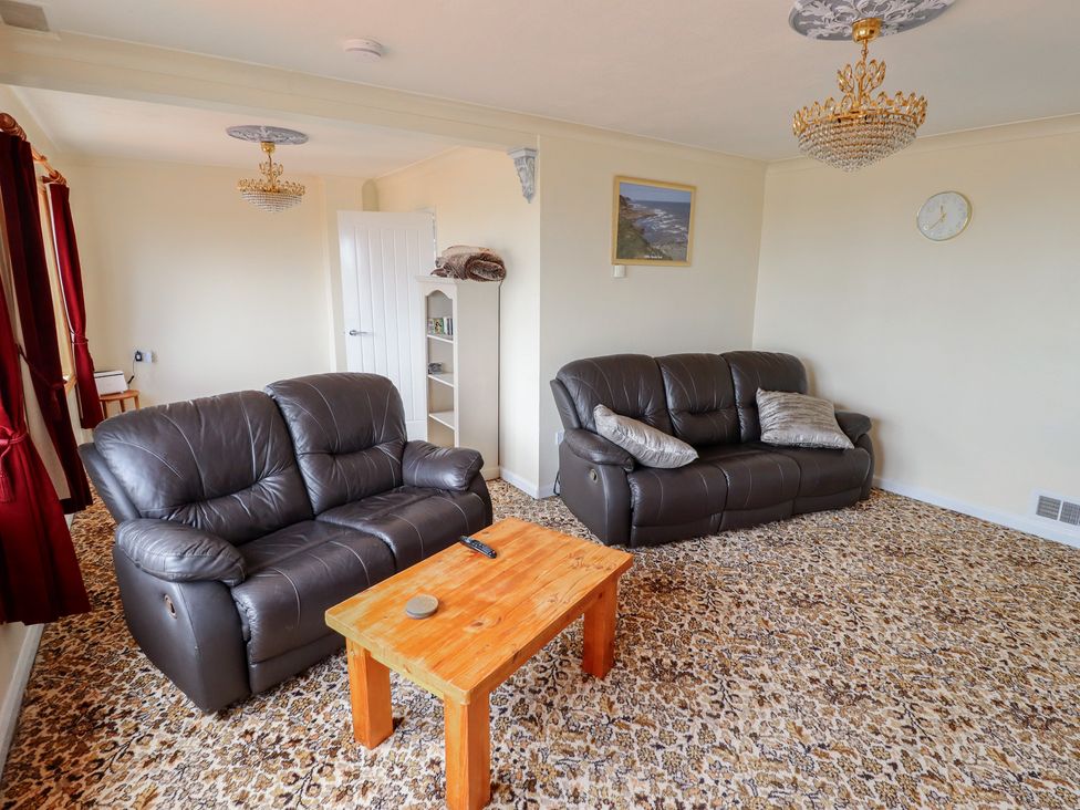 A living room with sofas and a wooden table at Sandringham in Withernsea