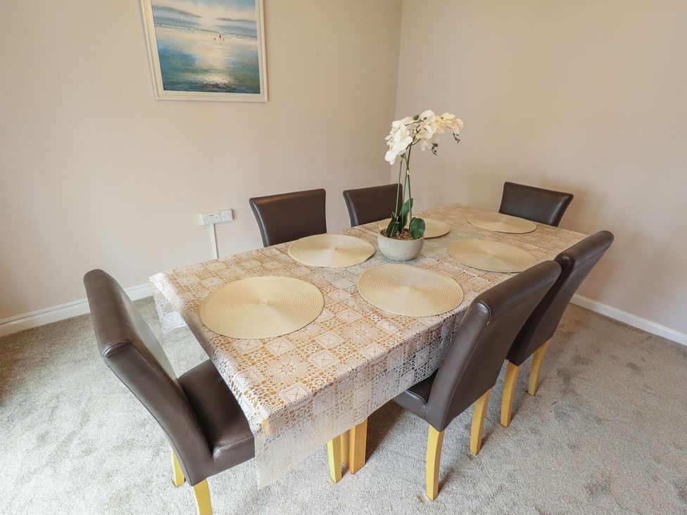 A dining table with chairs and a flower arrangement at Sandringham in Withernsea