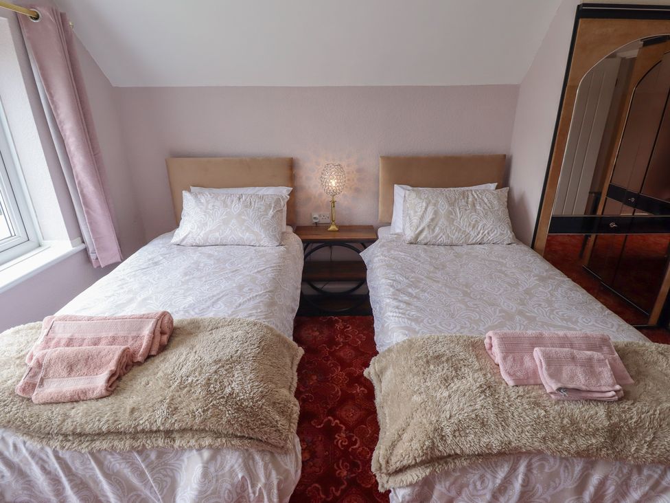 A bedroom with two beds and a lamp on a nightstand at Sandringham in Withernsea