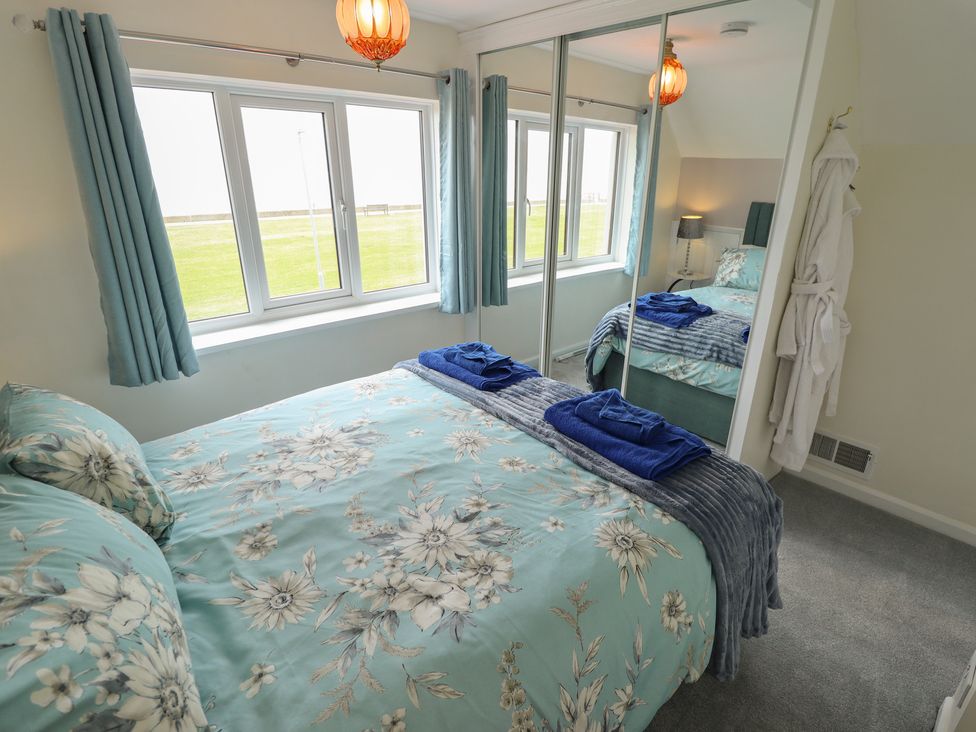 A bedroom with a bed and windows at Sandringham in Withernsea
