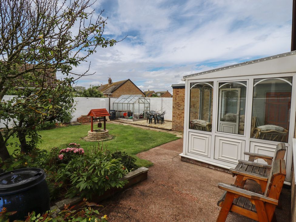 A garden with a greenhouse and seating area at Sandringham in Withernsea
