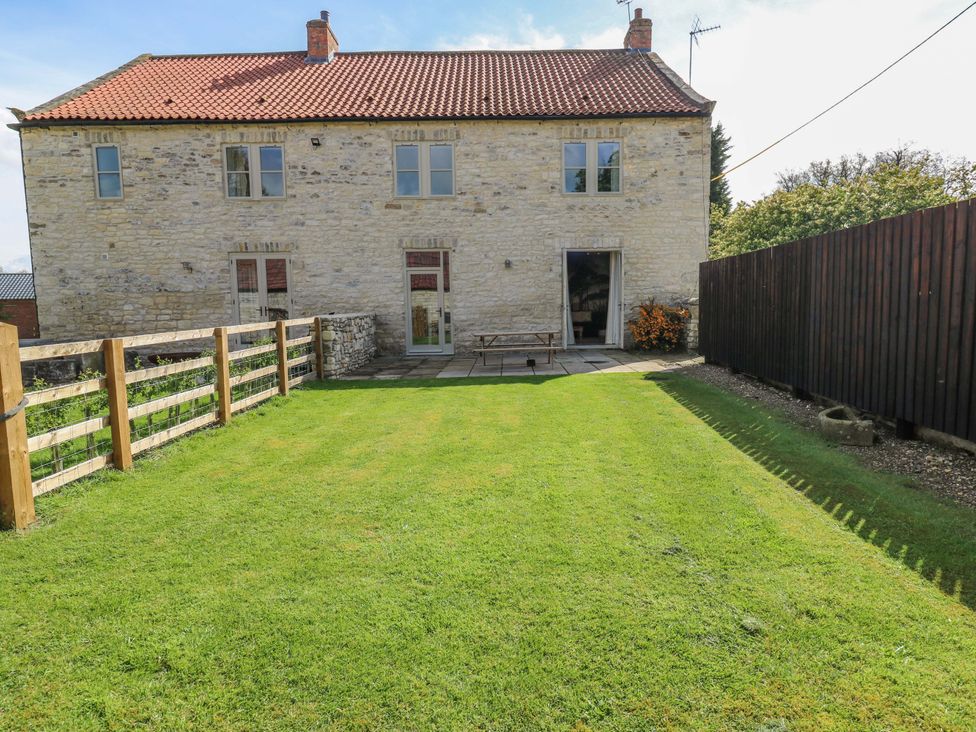 A garden with a table and a stone house at Stewards House in Tadcaster