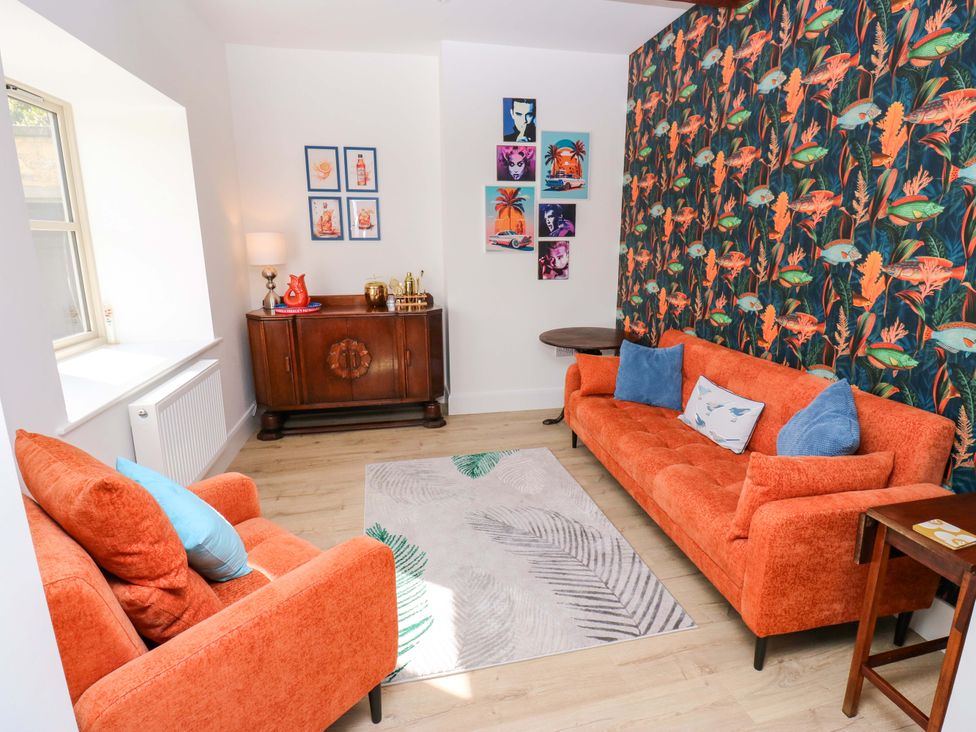 A living room with orange sofas and decorative pictures at Stewards House in Tadcaster
