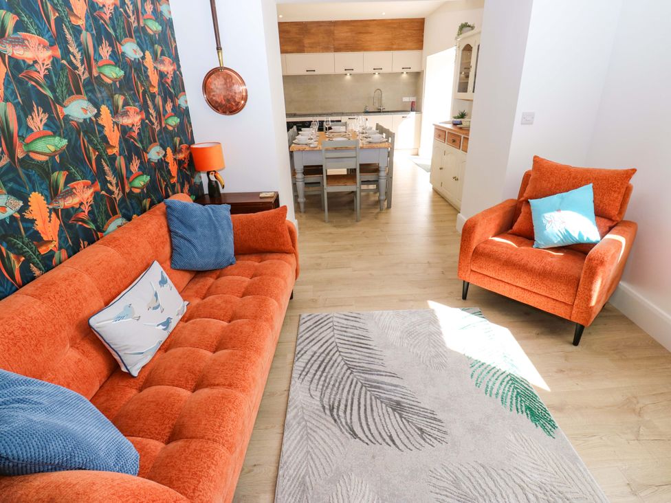 A living room with an orange sofa and dining area at Stewards House in Tadcaster