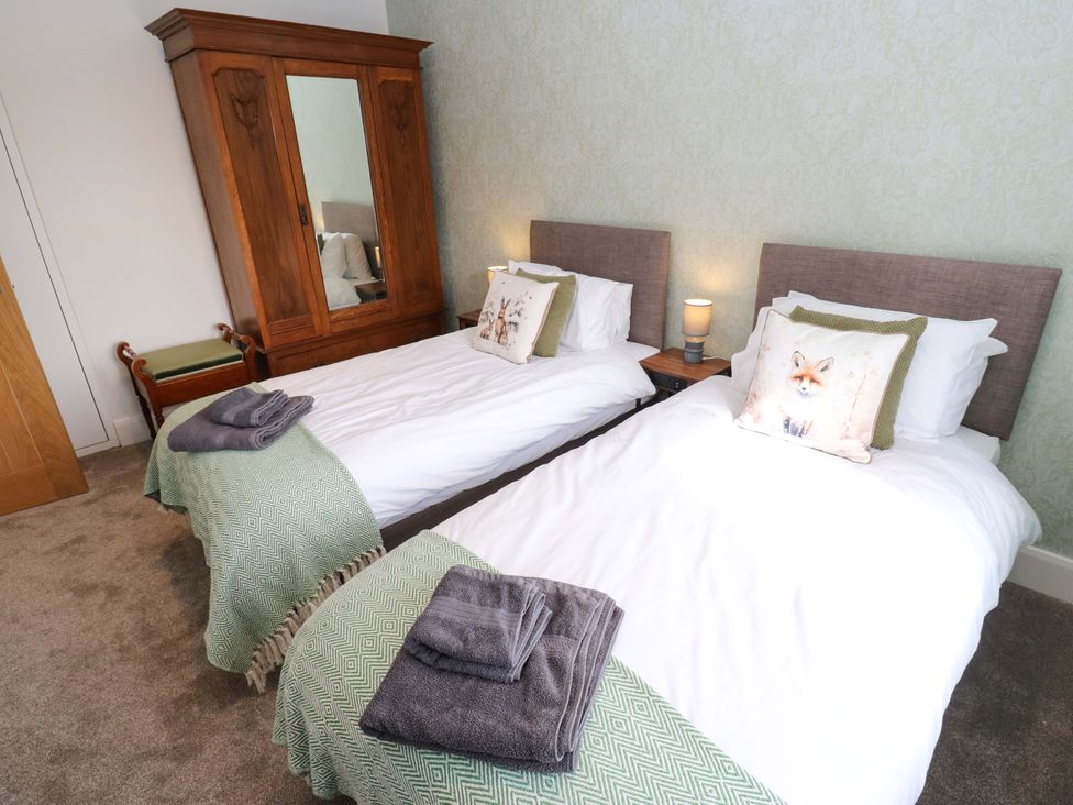 A bedroom with two single beds and a wardrobe at Stewards House in Tadcaster