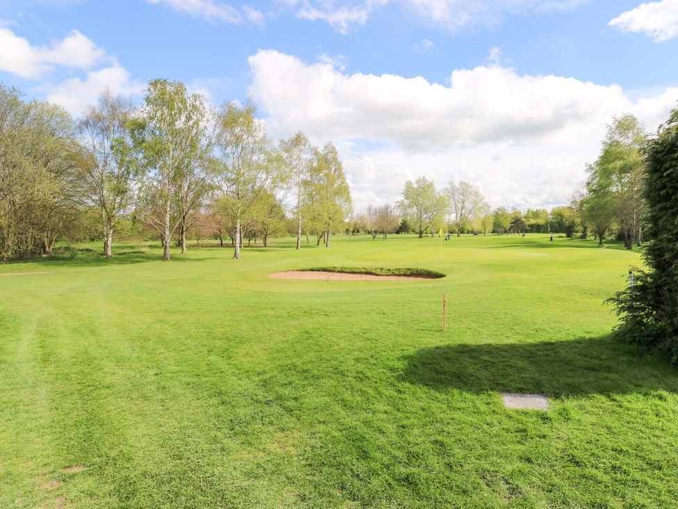 A golf course with a bunker and trees at Stewards House in Tadcaster
