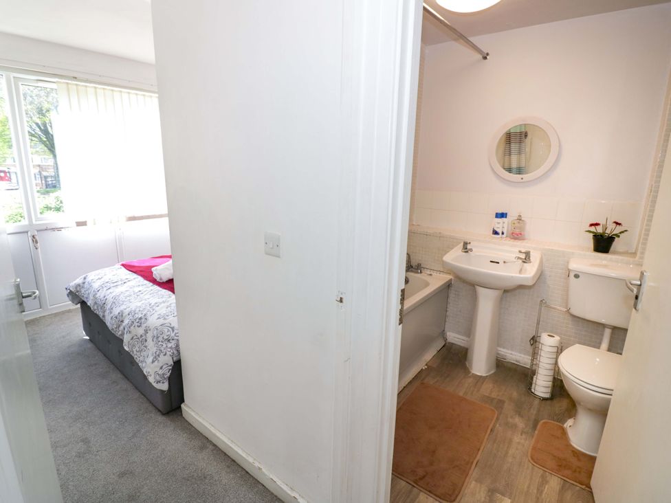 A bathroom with a sink and toilet and a bed visible from the doorway at 2 Carpenters Court in Birmingham