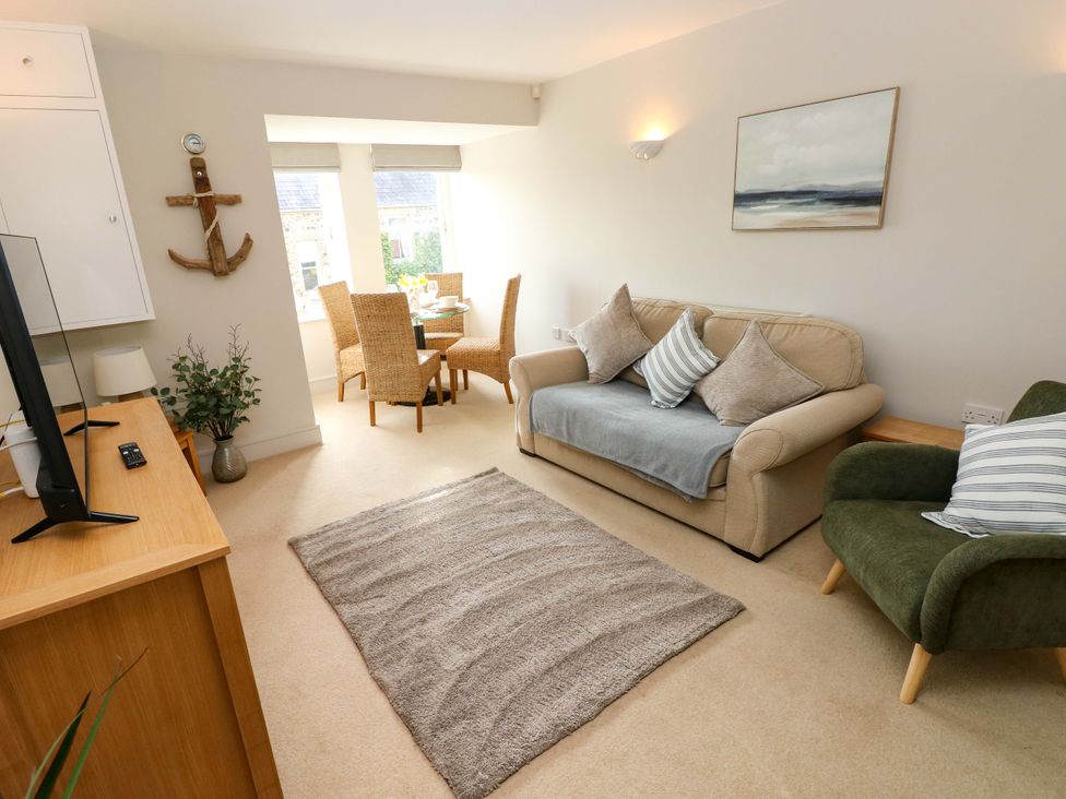 A living room with a sofa and dining area at 3 Rhodewood House Saundersfoot