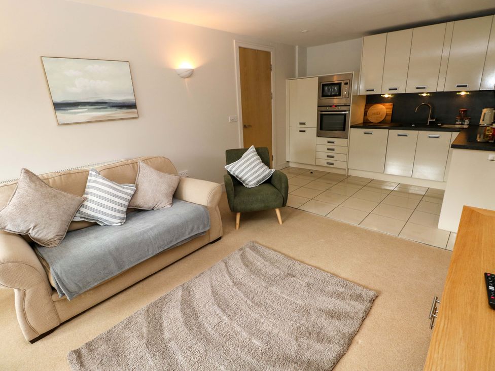 A living room with a sofa and kitchen area at 3 Rhodewood House in Saundersfoot