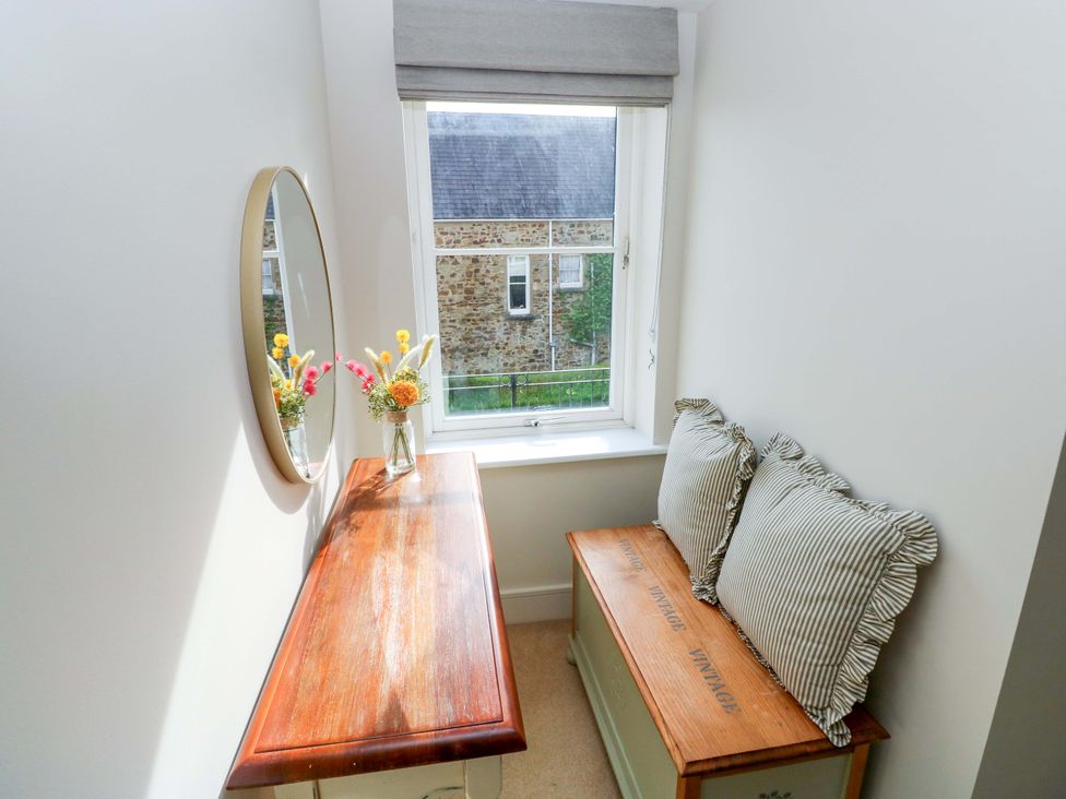 A sitting room with a table and cushions near a window at 3 Rhodewood House in Saundersfoot