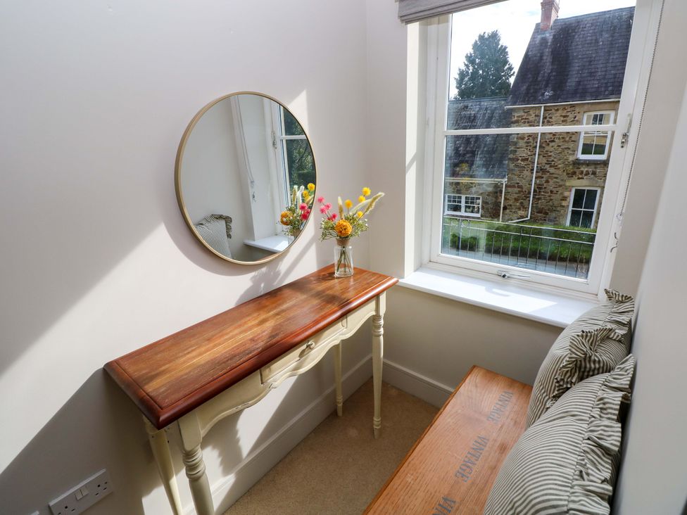 A snug with a table and flowers near a window at 3 Rhodewood House in Saundersfoot
