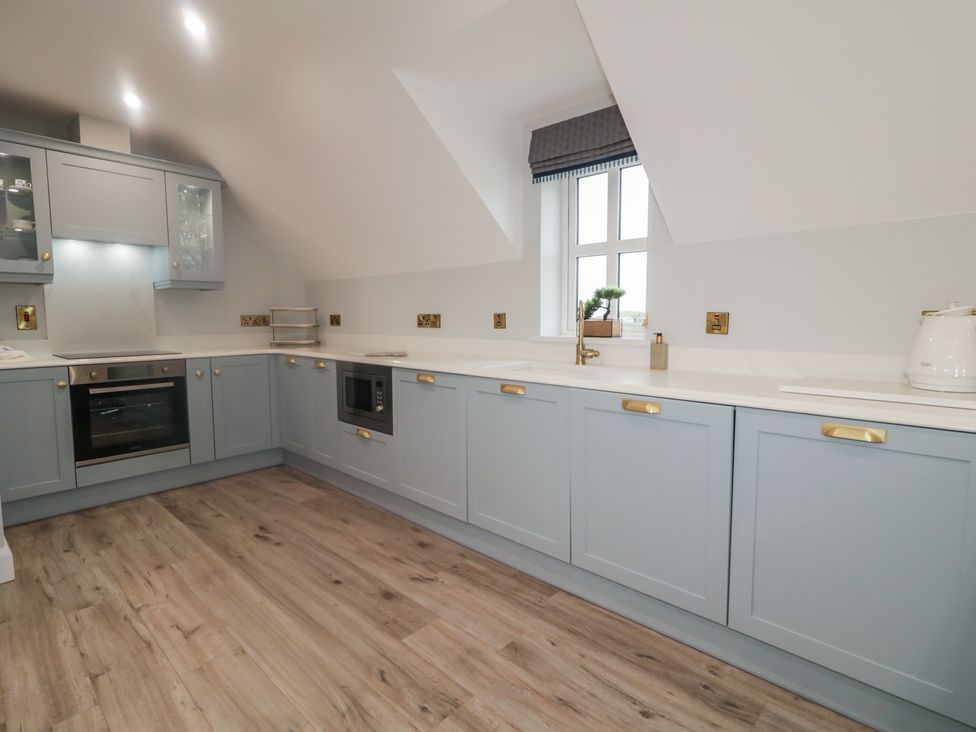 A kitchen with cabinets, oven, sink, and window at 2 Ard an Chuain Dunfanaghy