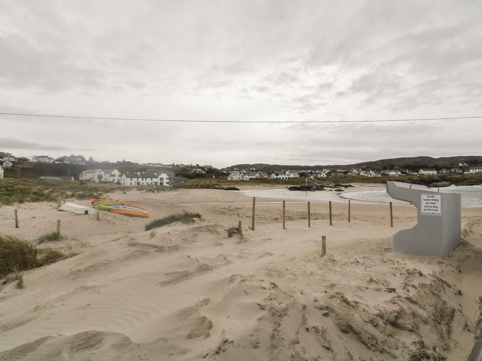 A beach with sand, water, houses in the background, and kayaks at 2 Ard an Chuain, Dunfanaghy