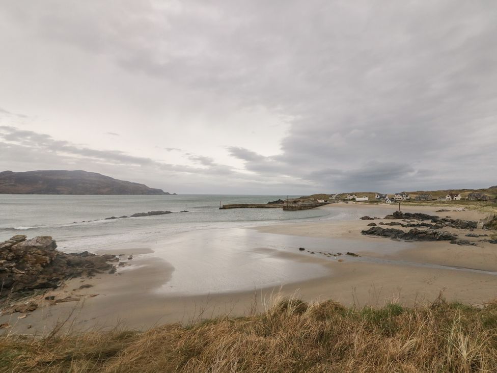 A beach with rocks and houses under a cloudy sky at 2 Ard an Chuain Dunfanaghy