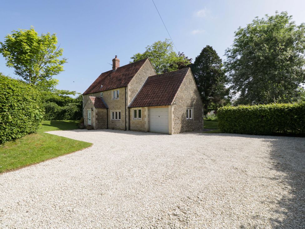 A house with a garage and driveway surrounded by trees at The Paddocks in Chippenham