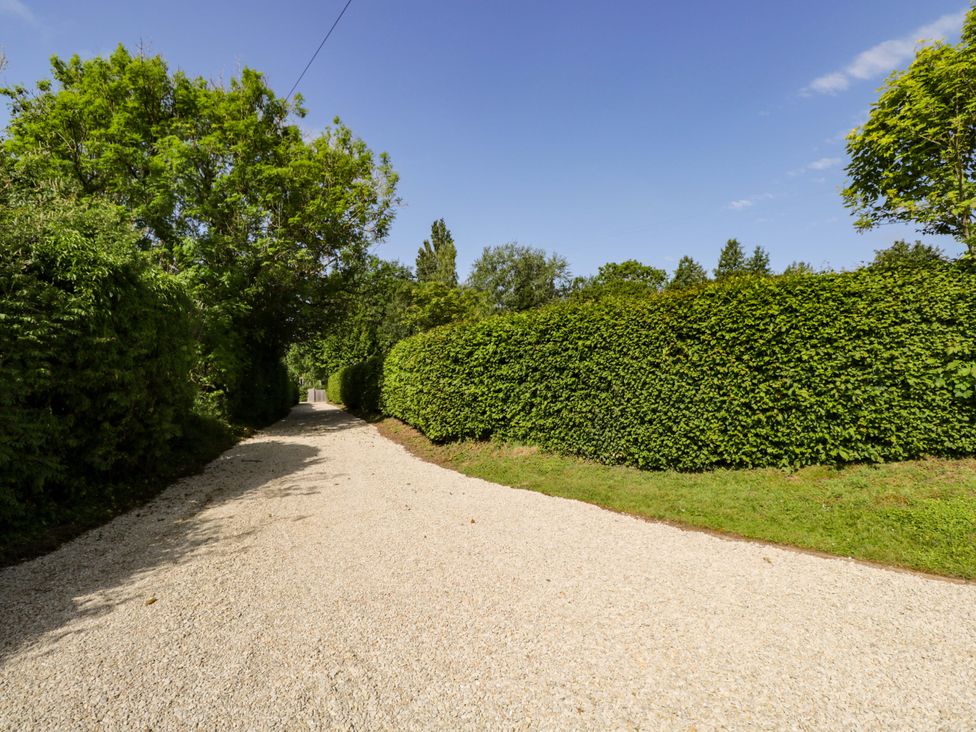 A gravel driveway lined with hedges and trees at The Paddocks in Chippenham