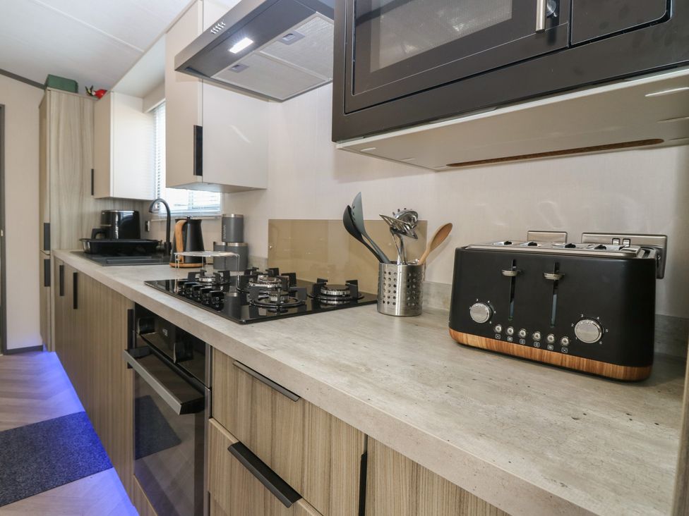 A kitchen with a microwave, toaster, gas stove, and kitchen utensils at Plot 243 - Coldingham Bay Leisure Park Eyemouth