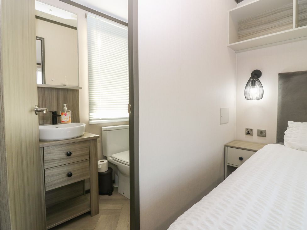 A bathroom with a sink and toilet adjacent to a bedroom at Plot 243 - Coldingham Bay Leisure Park Eyemouth