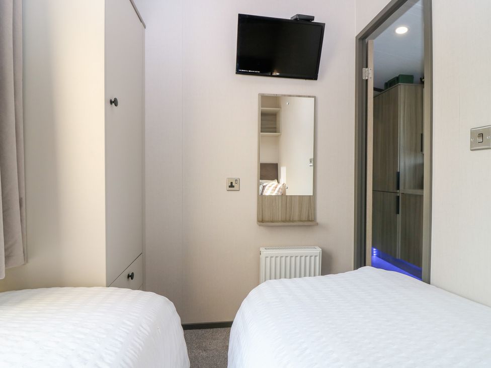 A bedroom with two beds, a television, and a wardrobe at Plot 243 - Coldingham Bay Leisure Park Eyemouth