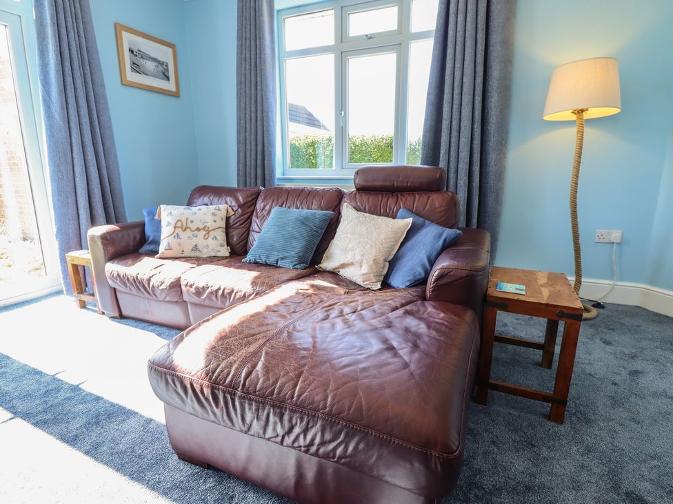 A living room with a sofa and lamp at Sorrento in Mablethorpe