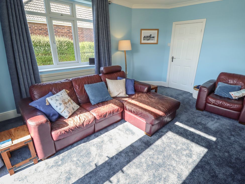 A living room with a sofa and lamp at Sorrento in Mablethorpe