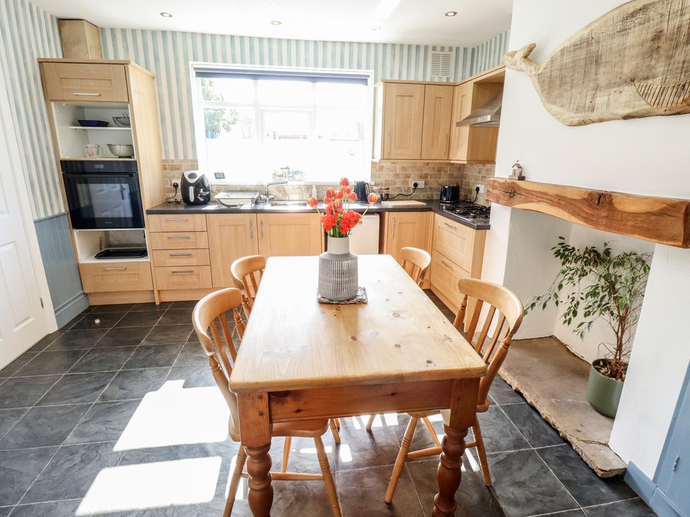 A kitchen with wooden cabinets and a dining table at Sorrento Mablethorpe