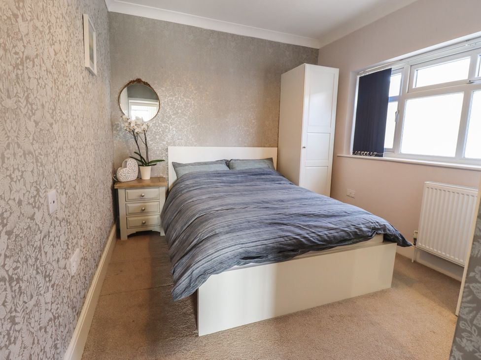 A bedroom with a bed and nightstand at Sorrento in Mablethorpe