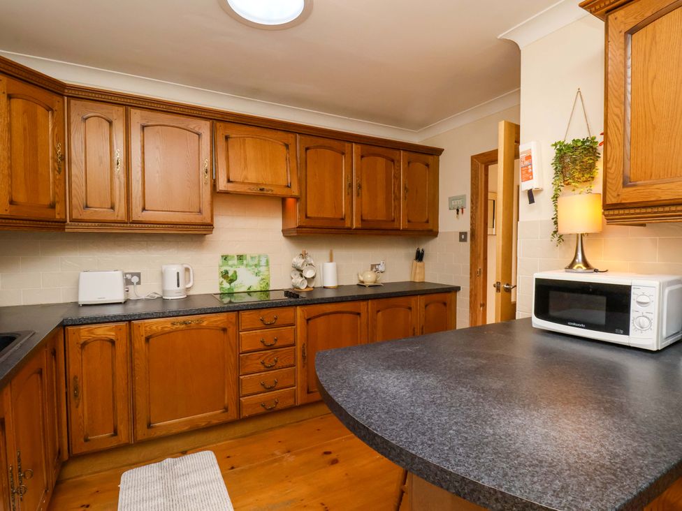 A kitchen with wooden cabinets and a microwave at The Nook in Robin Hood’s Bay