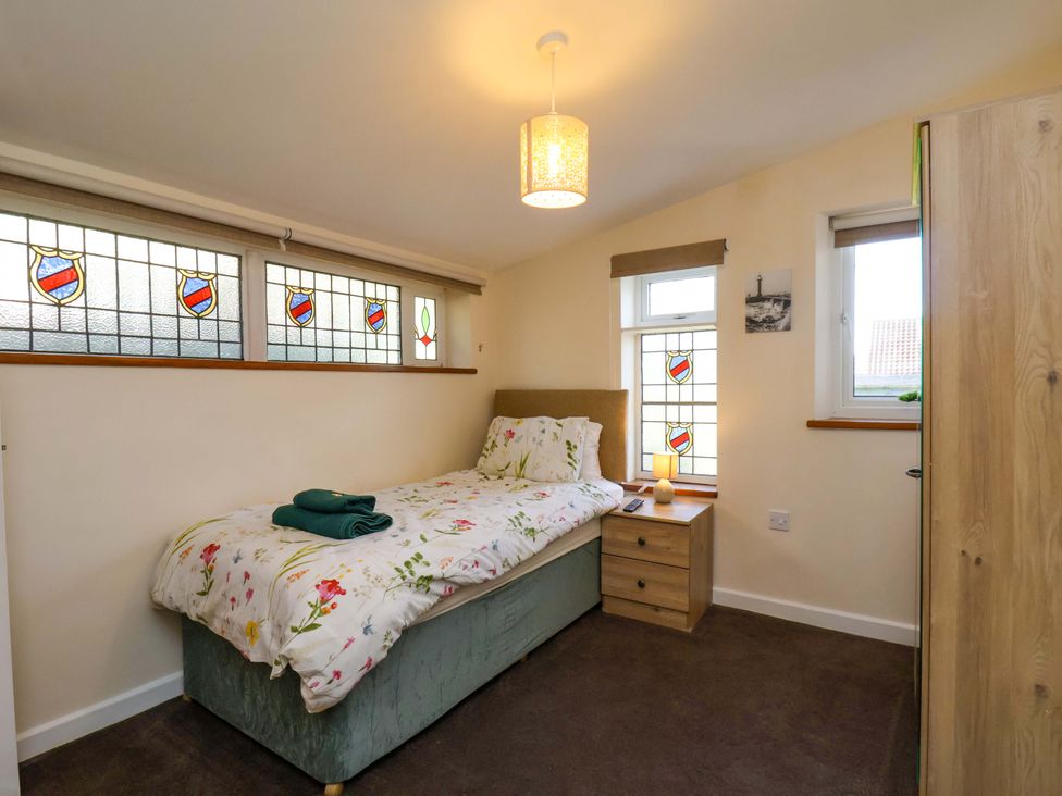 A bedroom with a bed and stained glass windows at The Nook in Robin Hood’s Bay